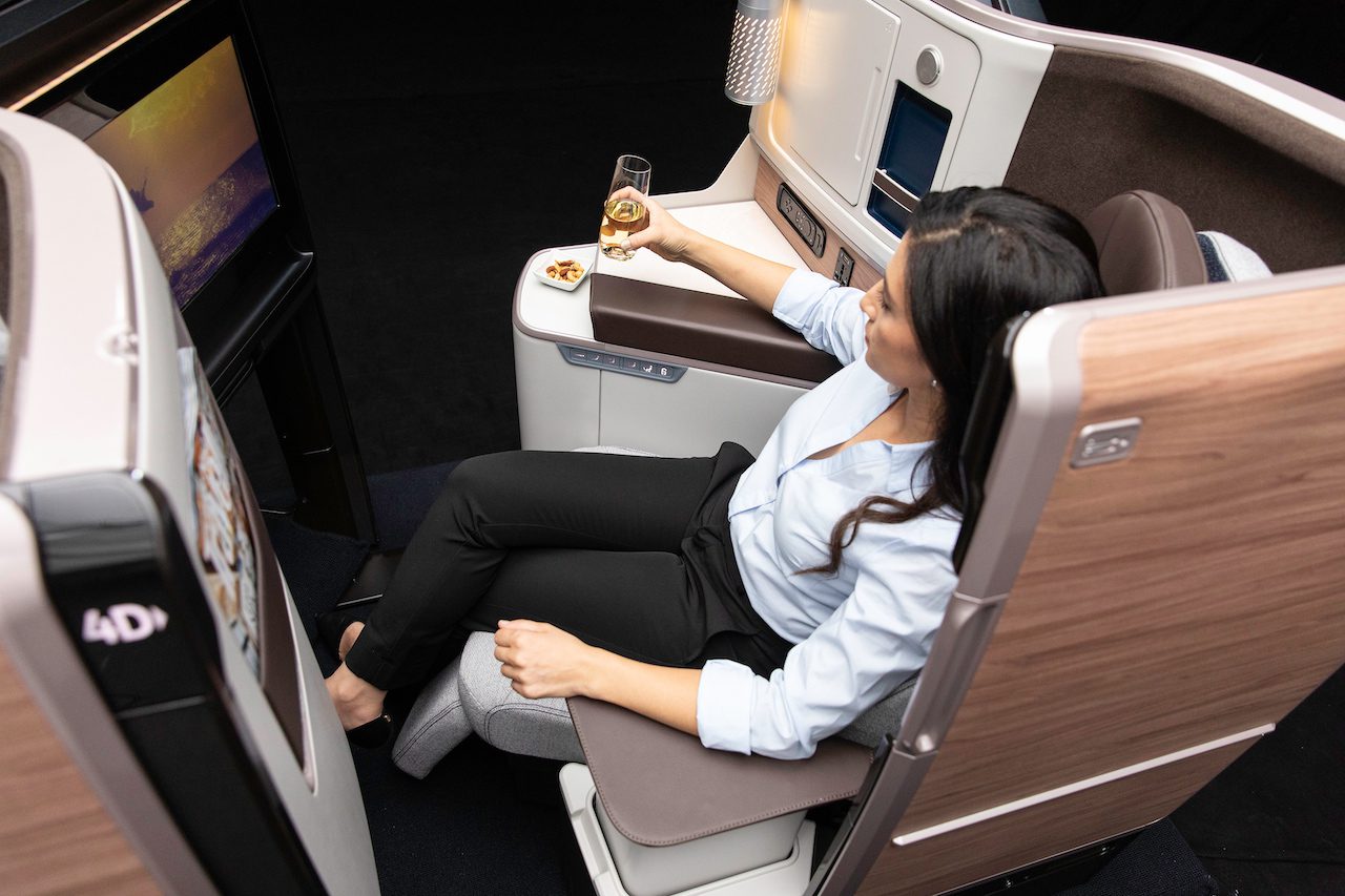 A woman passenger sitting in a business class seat on a plane. She has her elbows flat on the armrests.