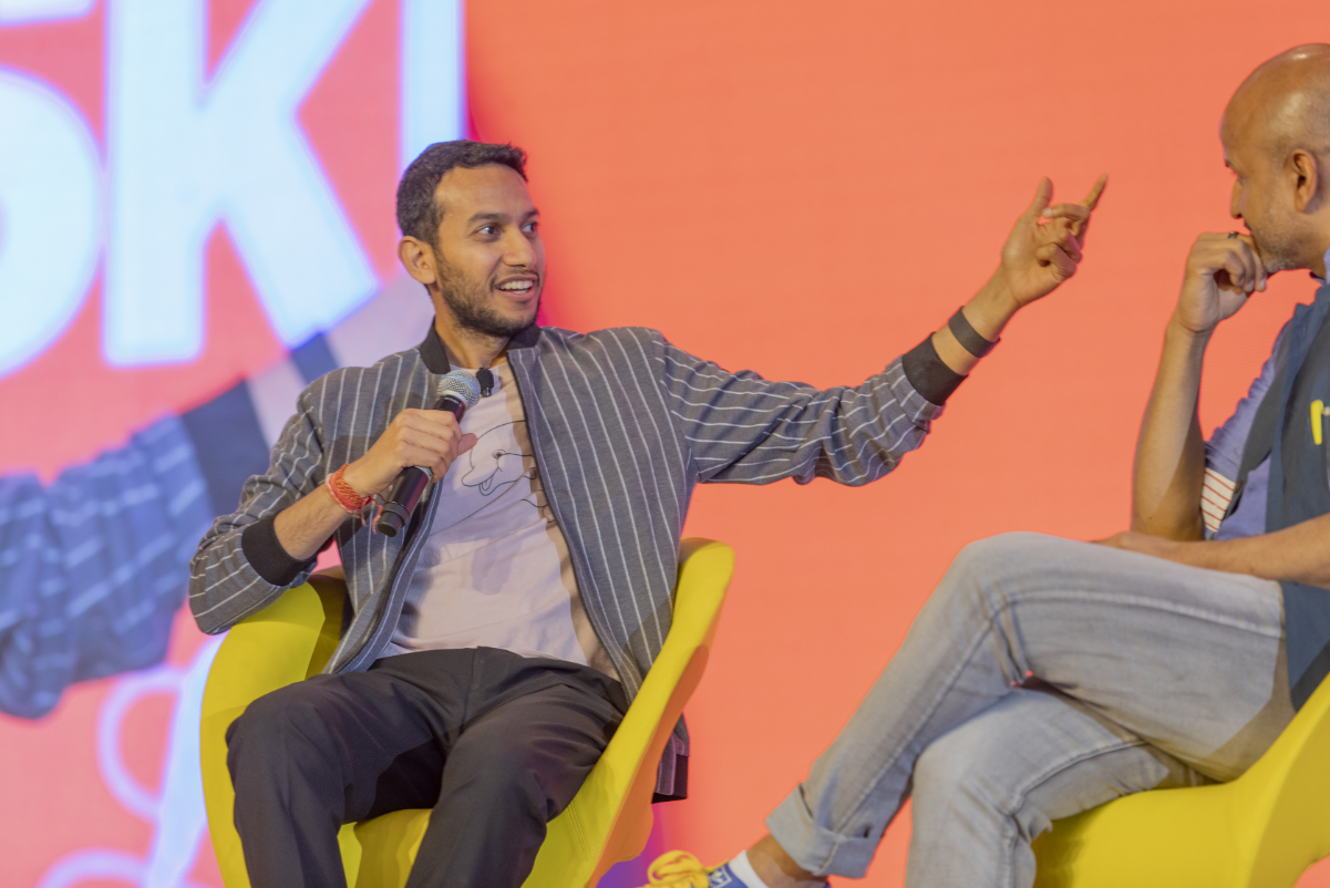 Two men speak on a stage.