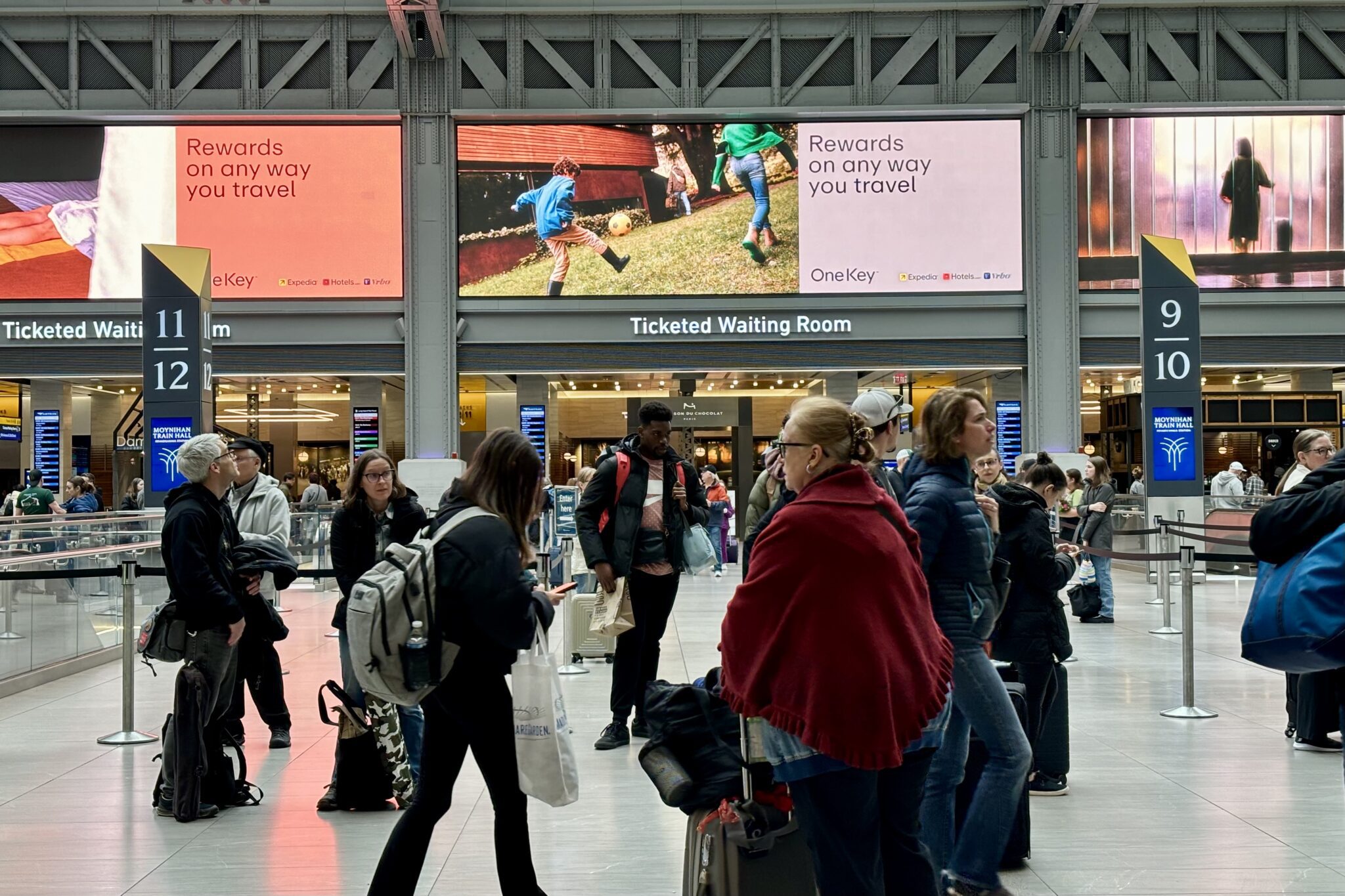 Crowded train station with large video advertisement boards in the background
