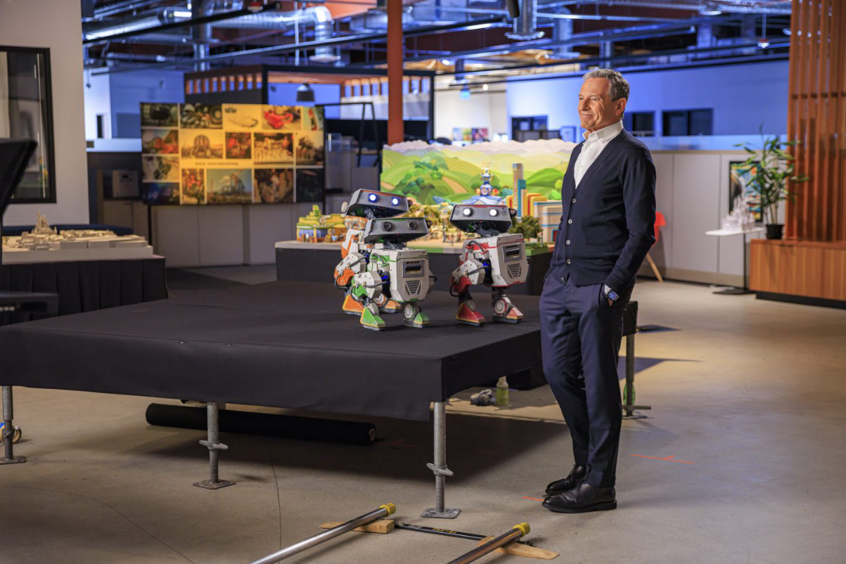 the ceo of walt disney company stands next to some new droids