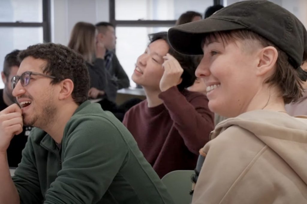 People in an office or classroom smiling at what they are looking at.