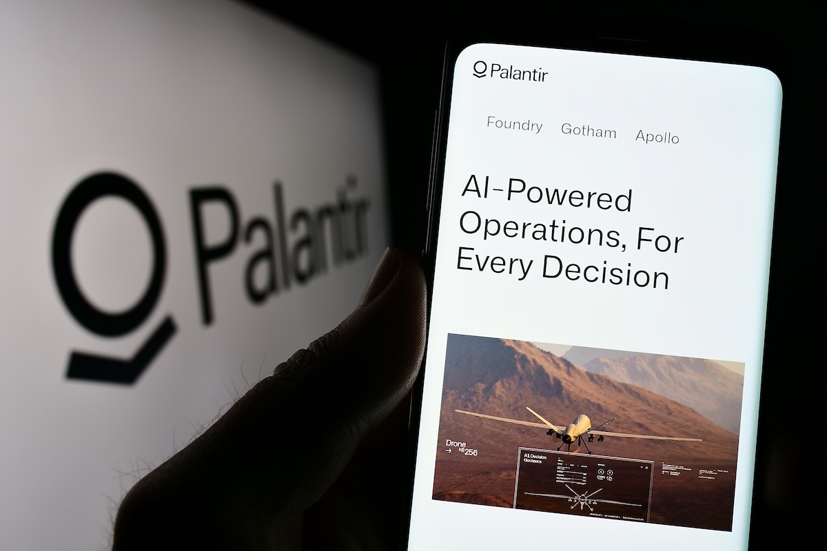 A person holding a smartphone with Palantir branding.