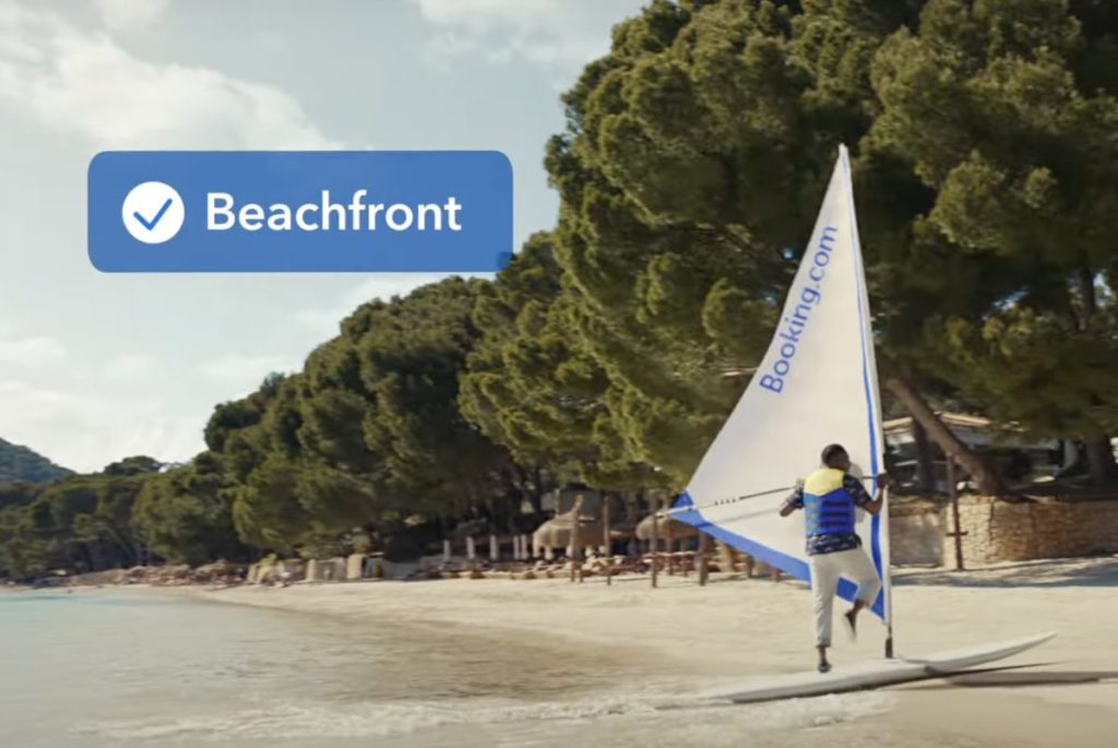 A person standing by a windsurfer on a beach.