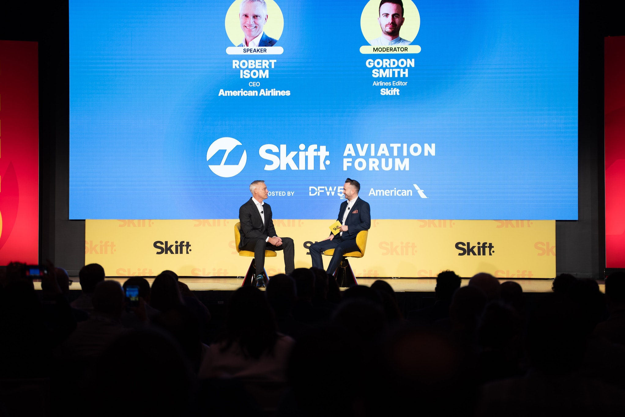 Robert Isom, CEO of American Airlines, and Gordon Smith of Skift Aviation Weekly speaking on stage at the Skift Aviation Forum, with event branding visible in the background.