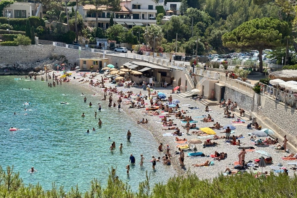 View of a beach filled with bathers next to blue waters