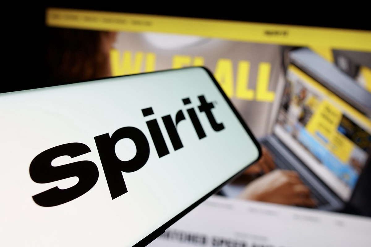A smartphone and computer screens showing Spirit Airlines’ logo and branding.