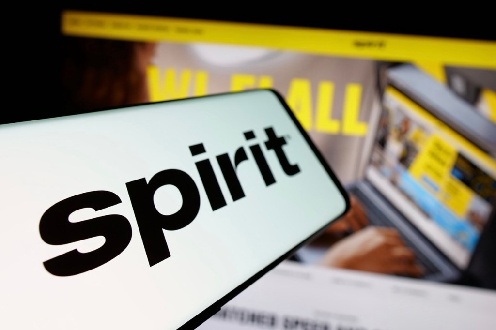 A smartphone and computer screens showing Spirit Airlines’ logo and branding.