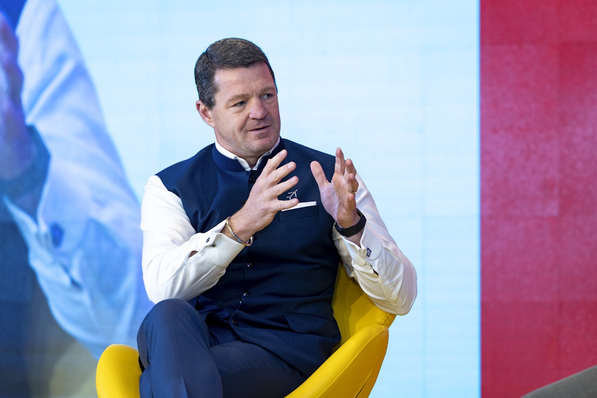 A man on stage gesturing with his hands as he speaks.