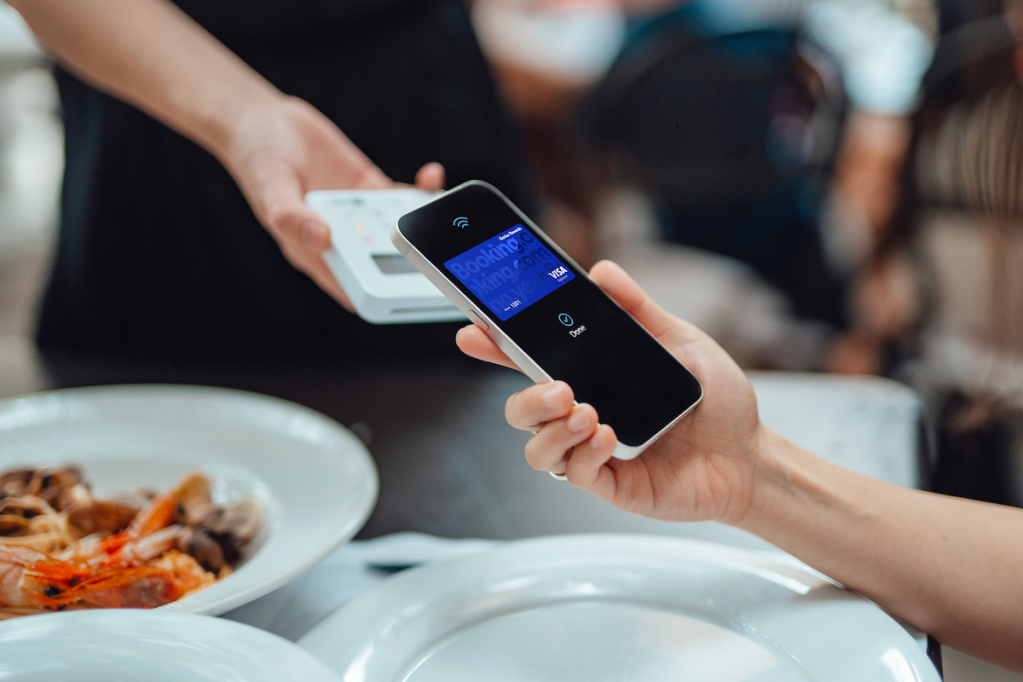 Someone holding a phone to pay for something with a Booking.com credit card.