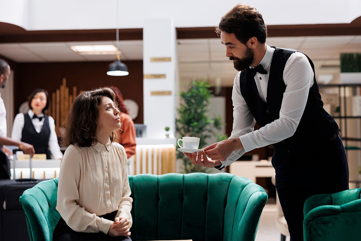 A waiter serving a cup of coffee ion a hotel lobby.