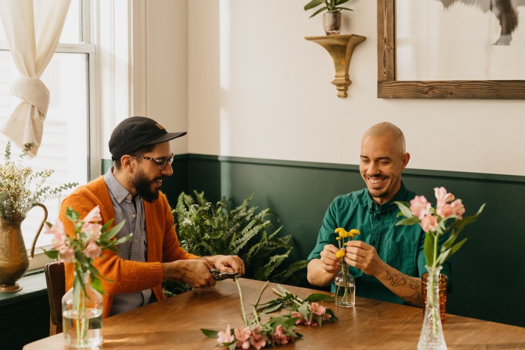An Airbnb superhost and guest sit at a dining room table in Chicago cutting and arranging flowers.
