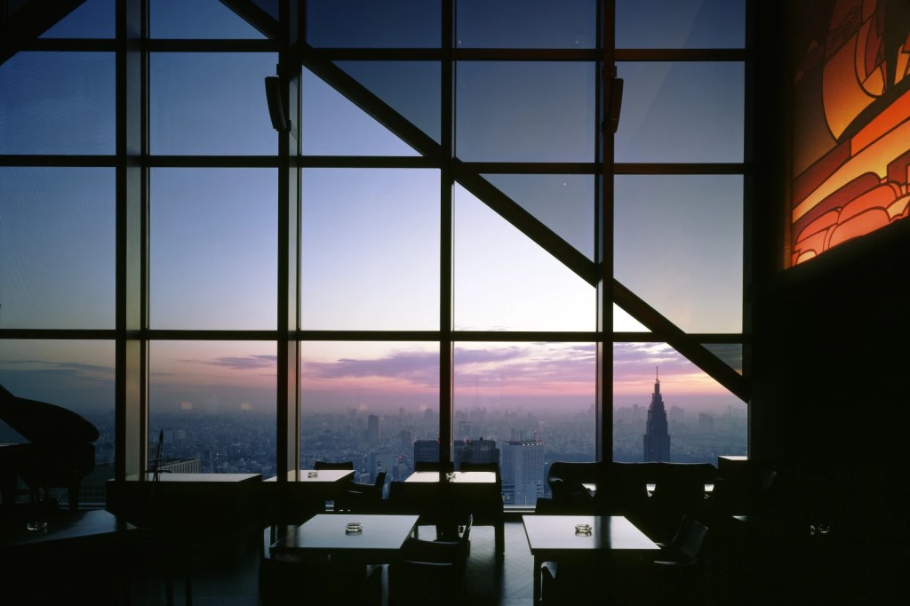 View of the Tokyo skyline from the New York Grill and Bar at the Park Hyatt Hotel. It's reopening in December 2025, seen at sunset.