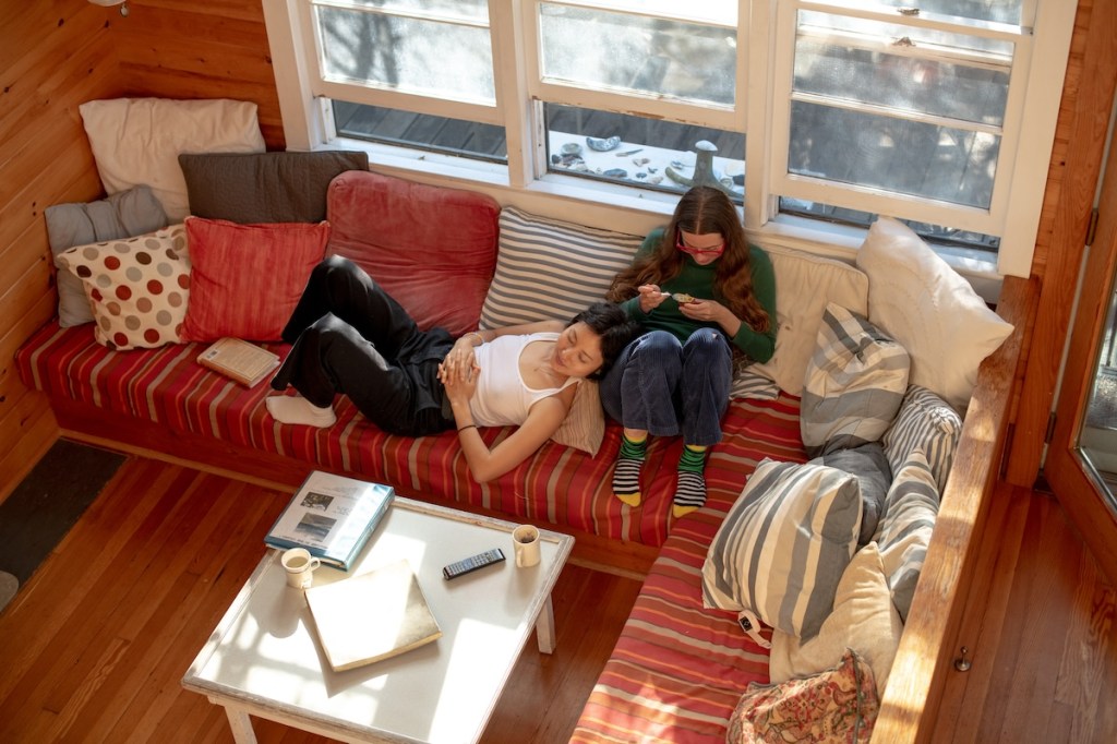 One guest in an Airbnb lying on a couch, and another sitting.