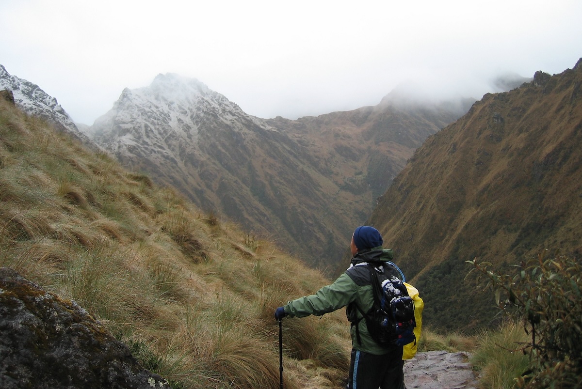 A backpacker gazing up at Machu Picchu on a gray, cloudy day.