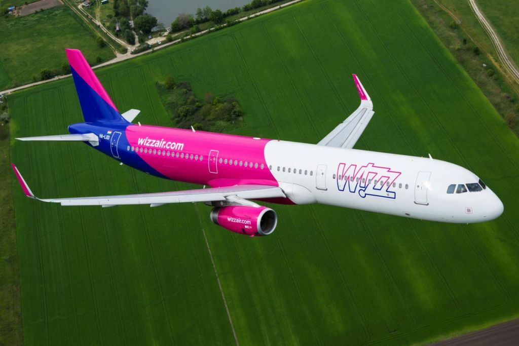 A Wizz Air A321 flying over a field.