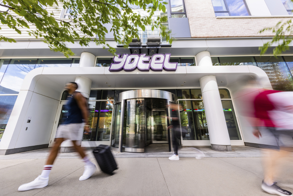 image of a guest walking outside of a Boston Yotel hotel on a sunny day