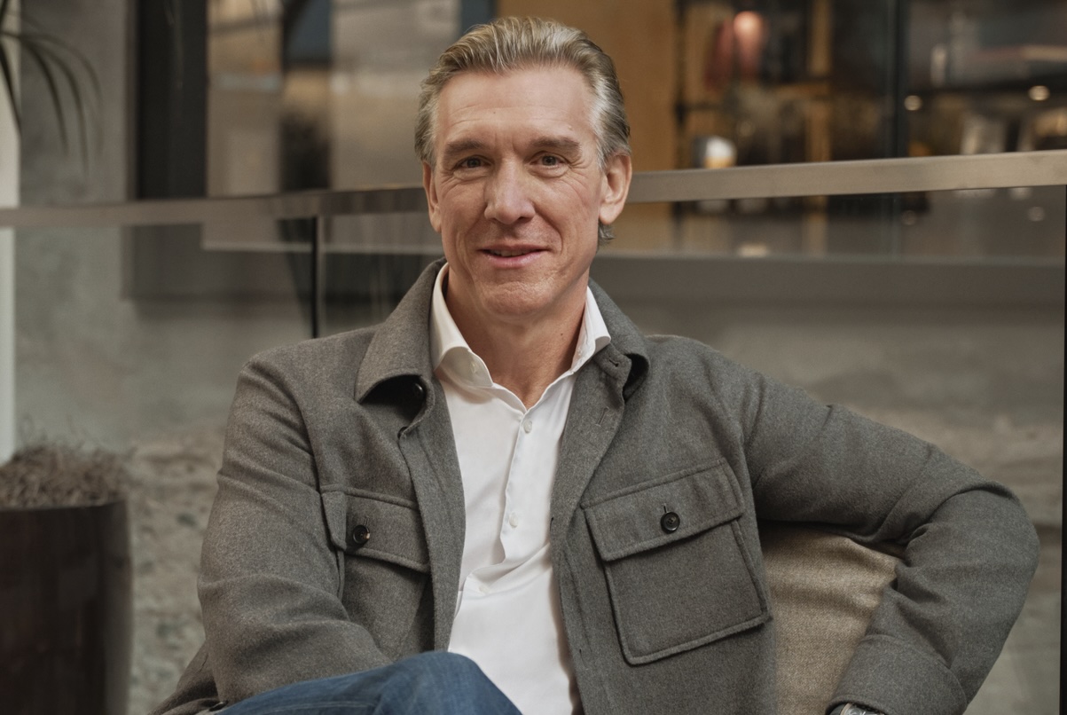A man in a gray jacket sitting in a chair.