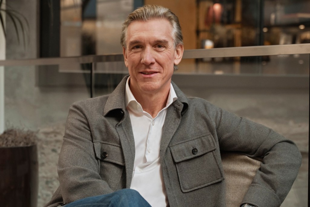A man in a gray jacket sitting in a chair.
