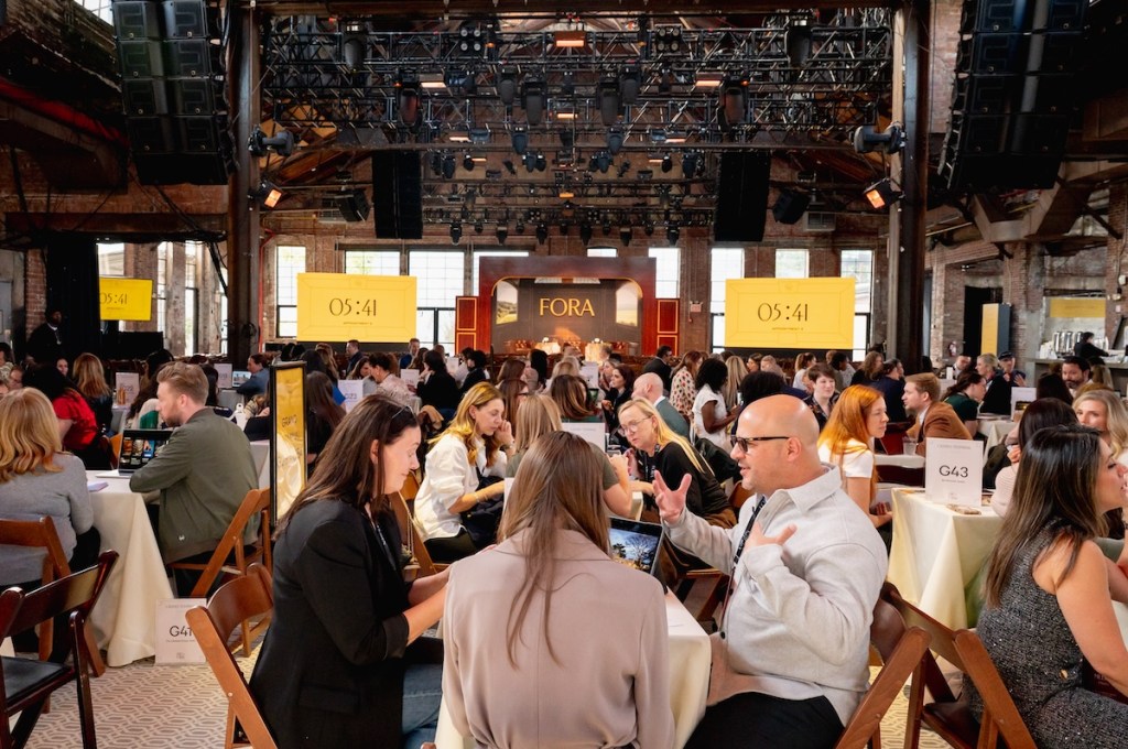 People sitting around tables and talking at Fora Travel event.